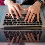 person using macbook pro on blue textile